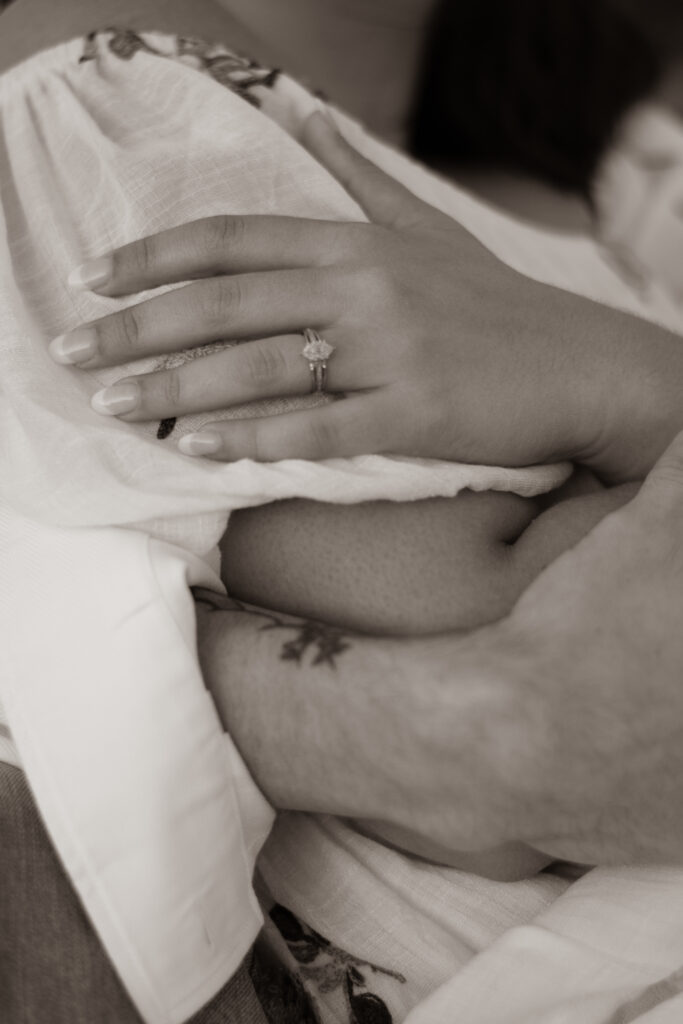 Newly engaged couple embraced, emphasis on modest engagement ring