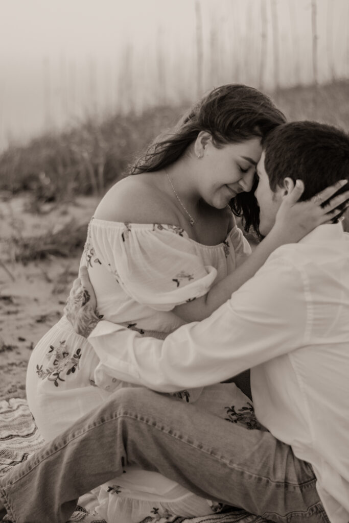 A couple embraces while sitting on the beach during their Big Island Elopement