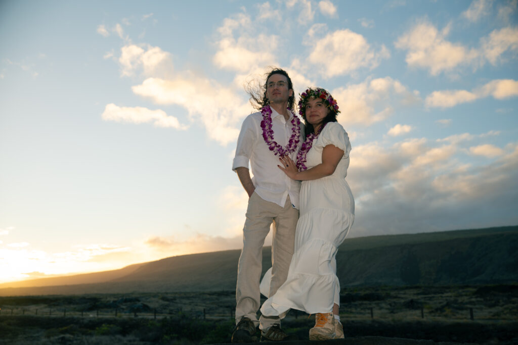 A couple in wedding clothes and hiking boots pose for a portrait