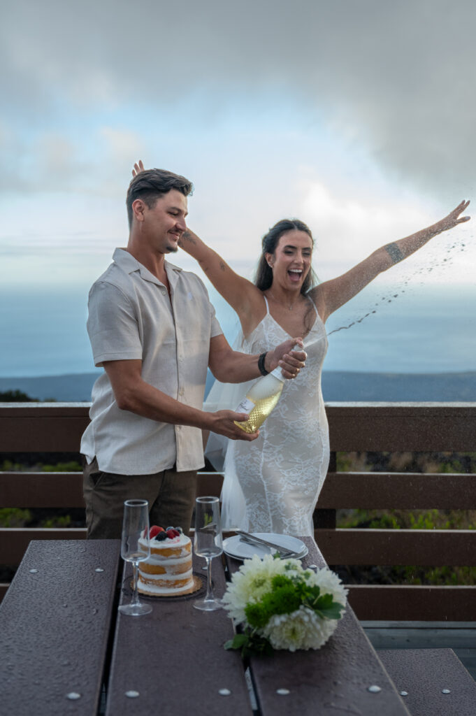 A beautiful couple celebrates their elopement with cake and champagne in Hawai'i's Volcano National Park