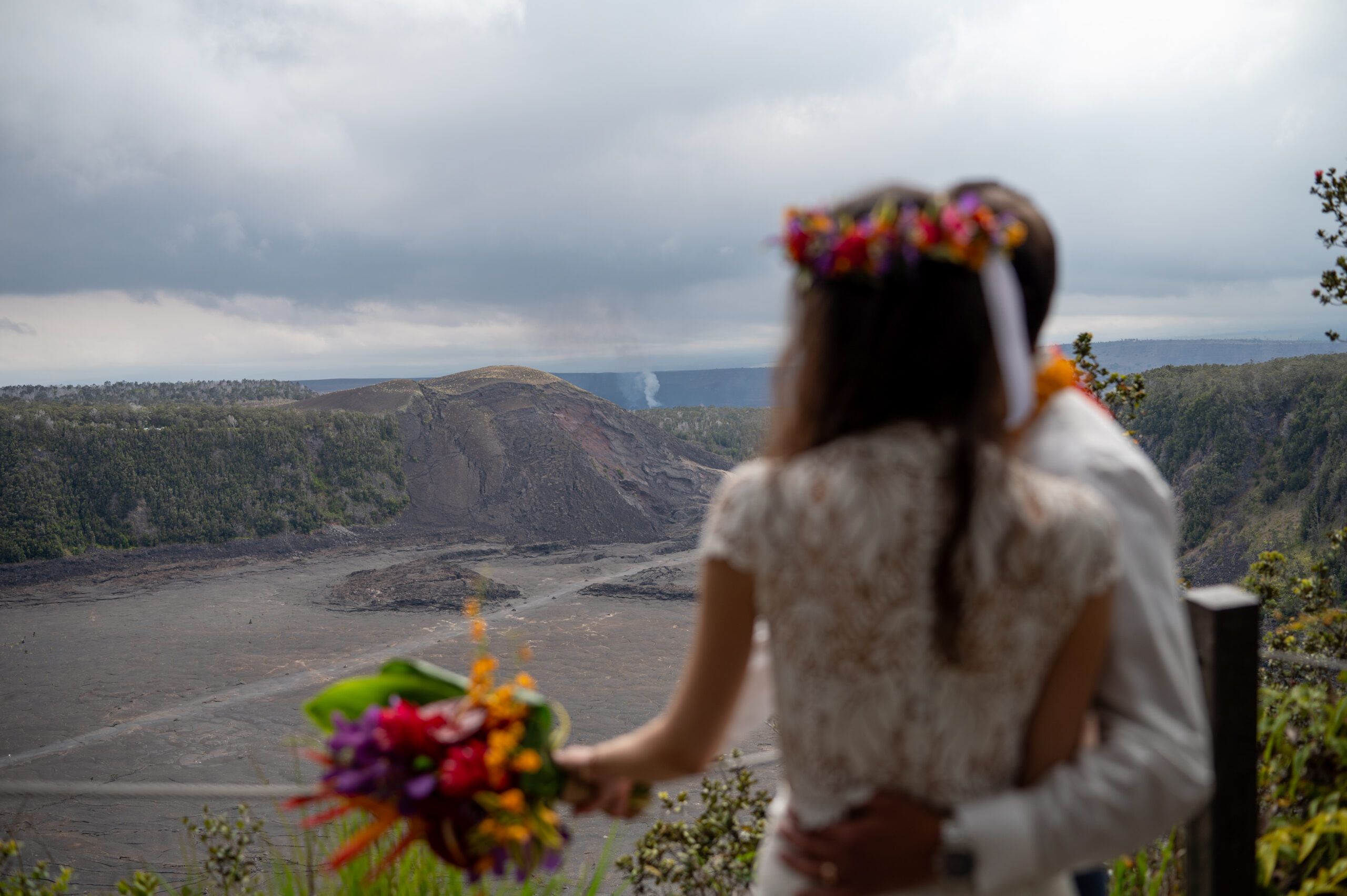 A couple in wedding clothes looks at Kilauea volcano