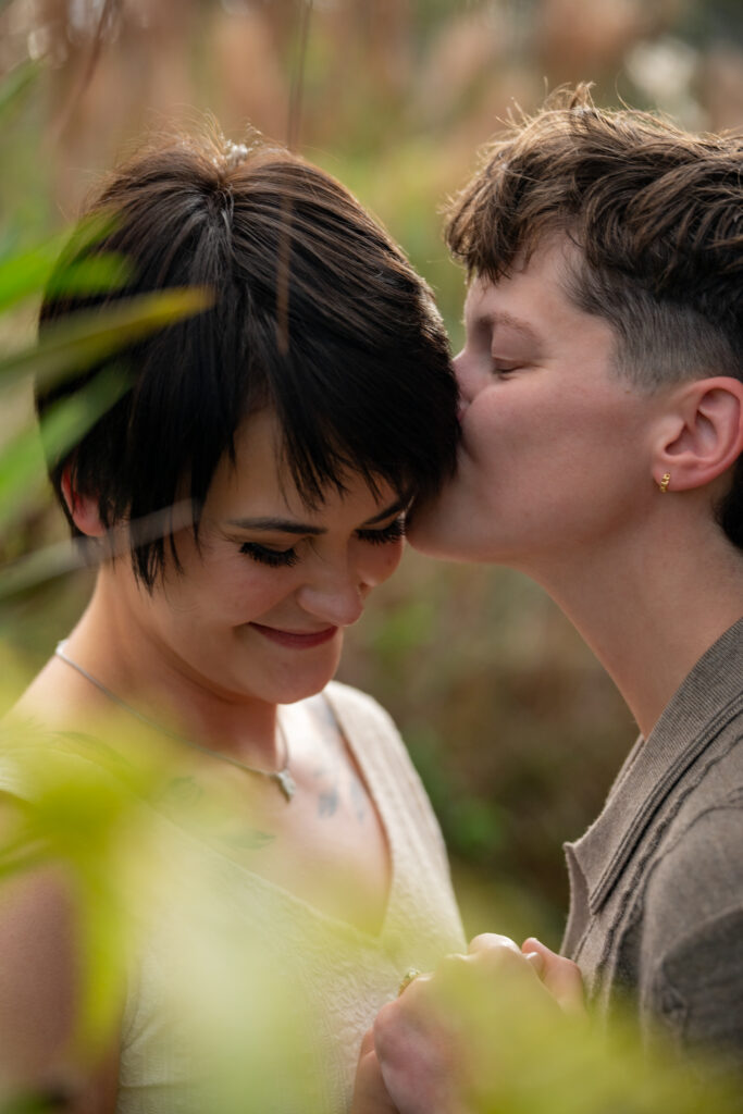 A woman kisses another woman on the cheek as they embrace