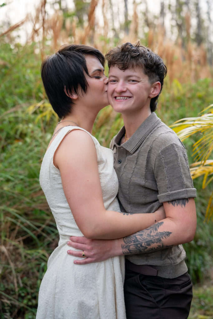 A woman kisses another woman on the cheek as they embrace