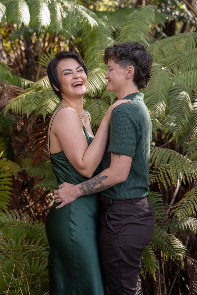 A couple embrace in front of giant ferns