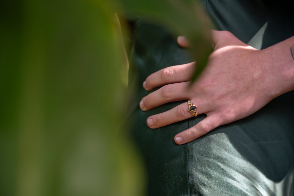 A woman's hand is on another woman's hip showing off an engagement ring.