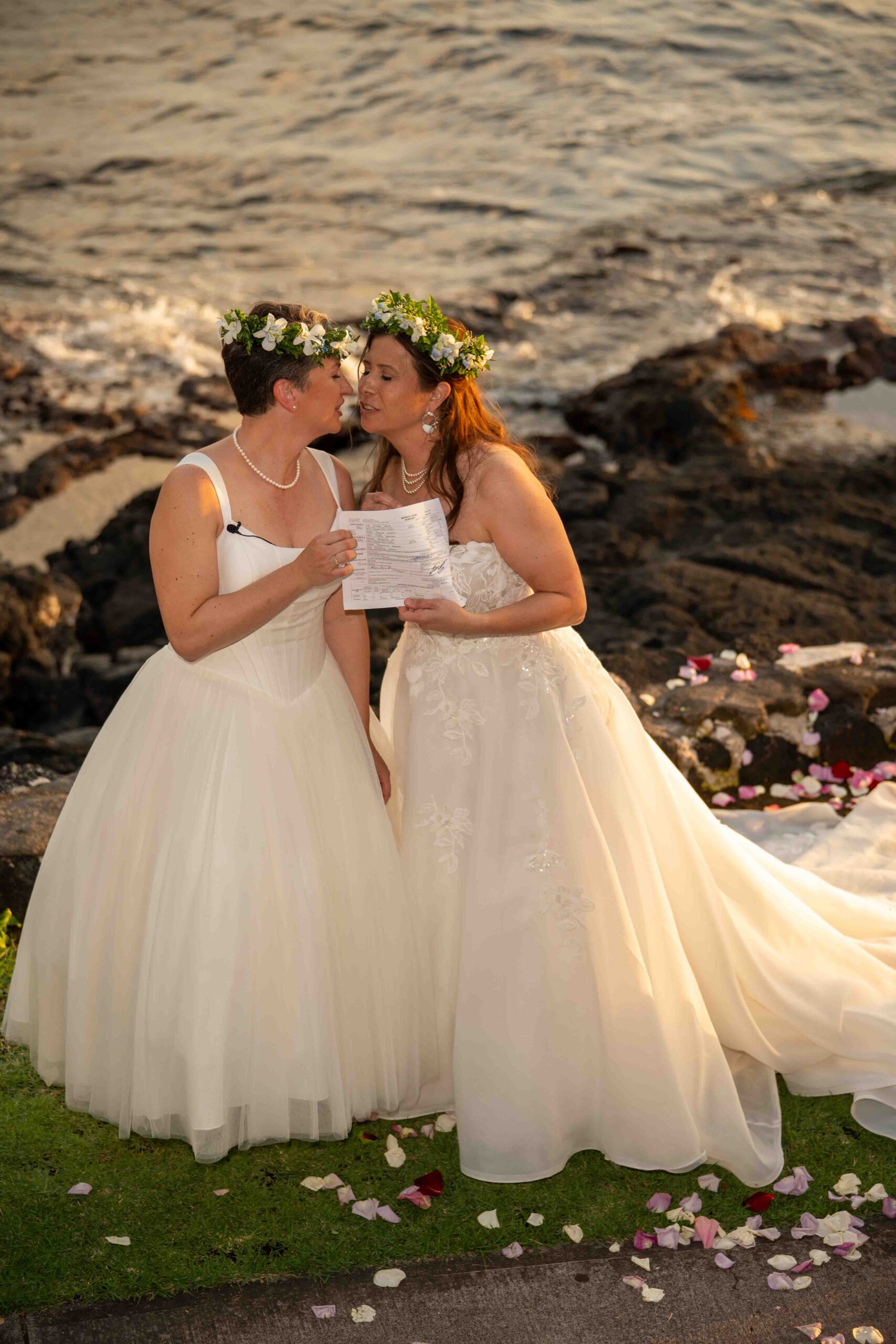Two brides kiss and hold up their marriage license after getting married at Papa Kona