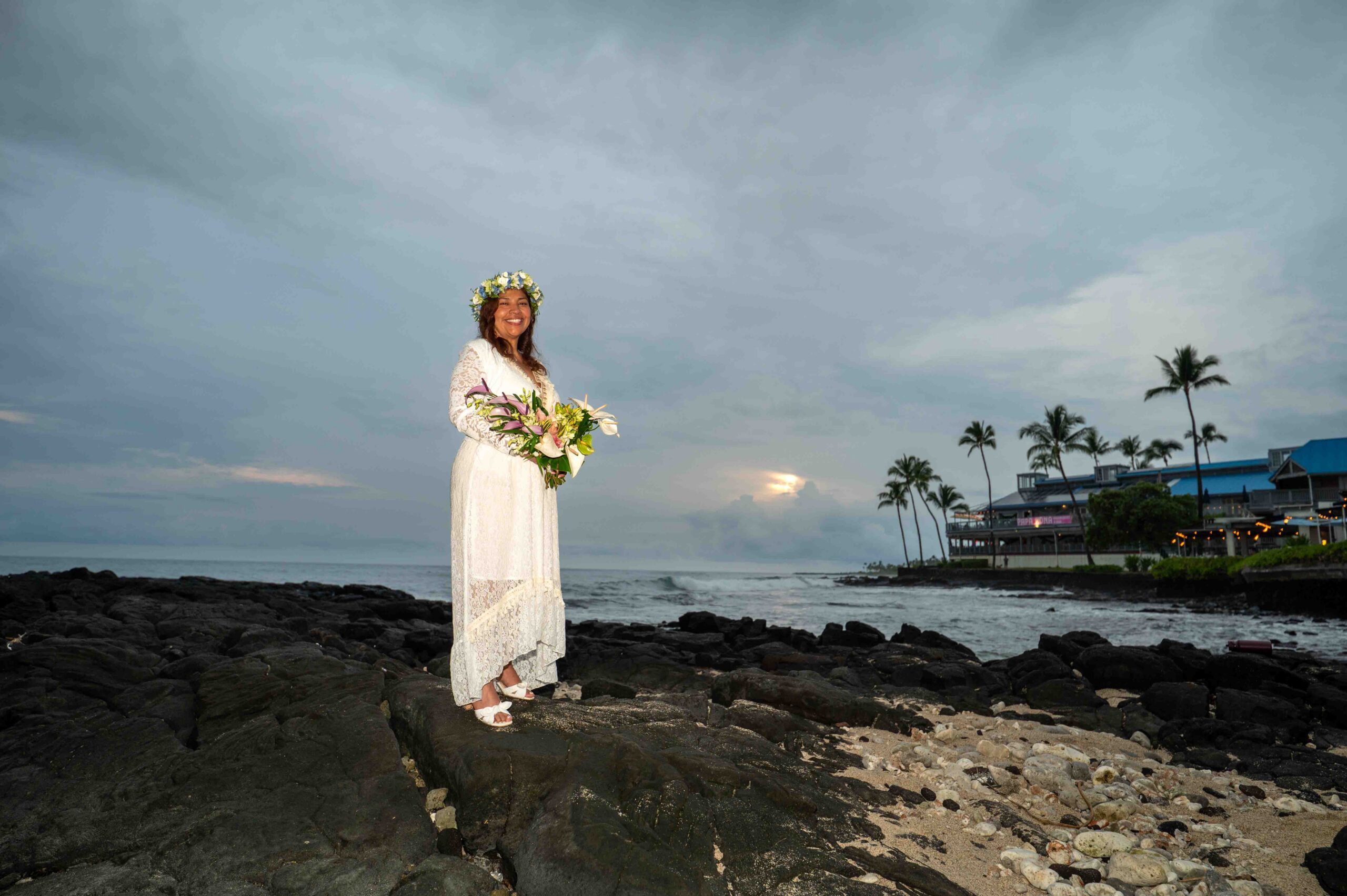 A bride stands on lava rocks at the beach after her Papa Kona Wedding