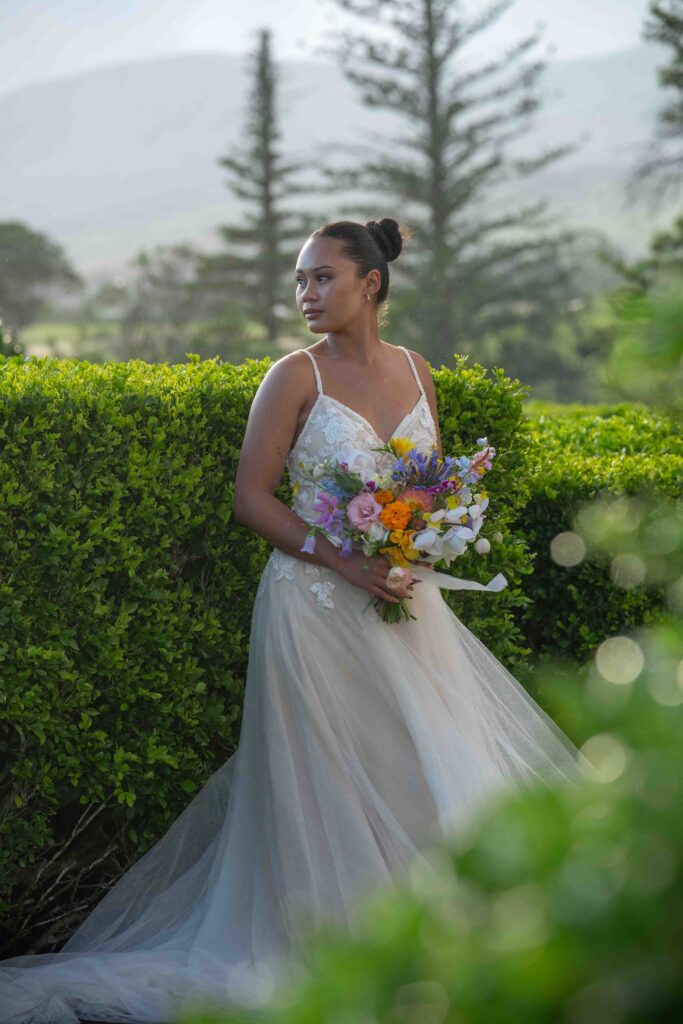 A bride stands with her bouquet in a garden