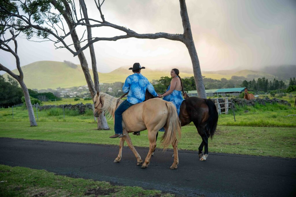 A couple rides horses and holds hands