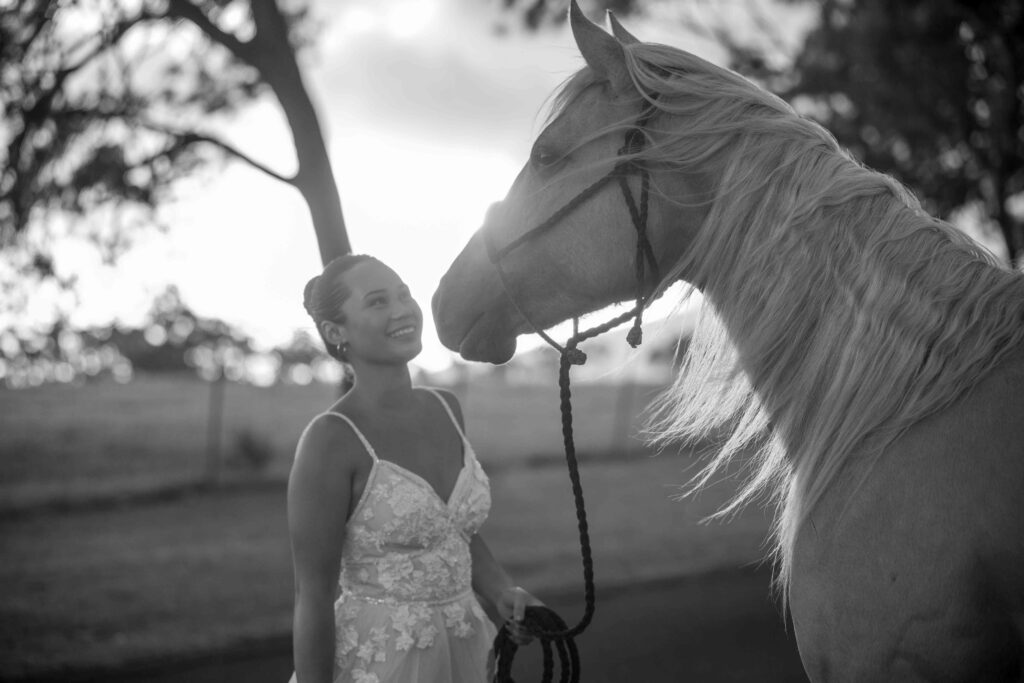 A bride smiles at her horse at sunset