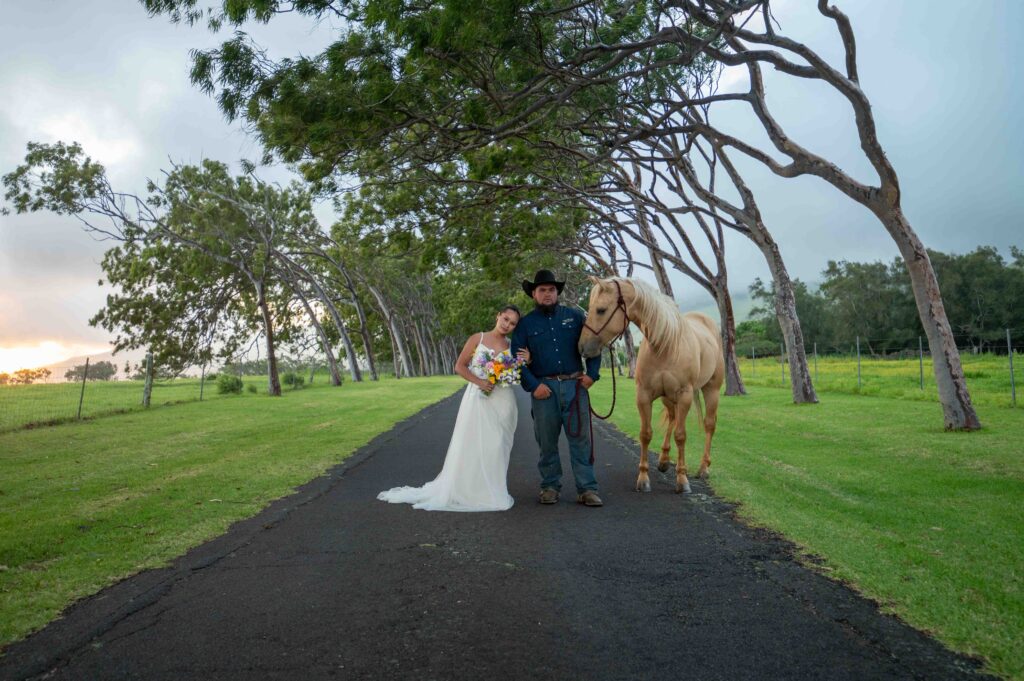 A married couple stands with a horse on a tree lined street