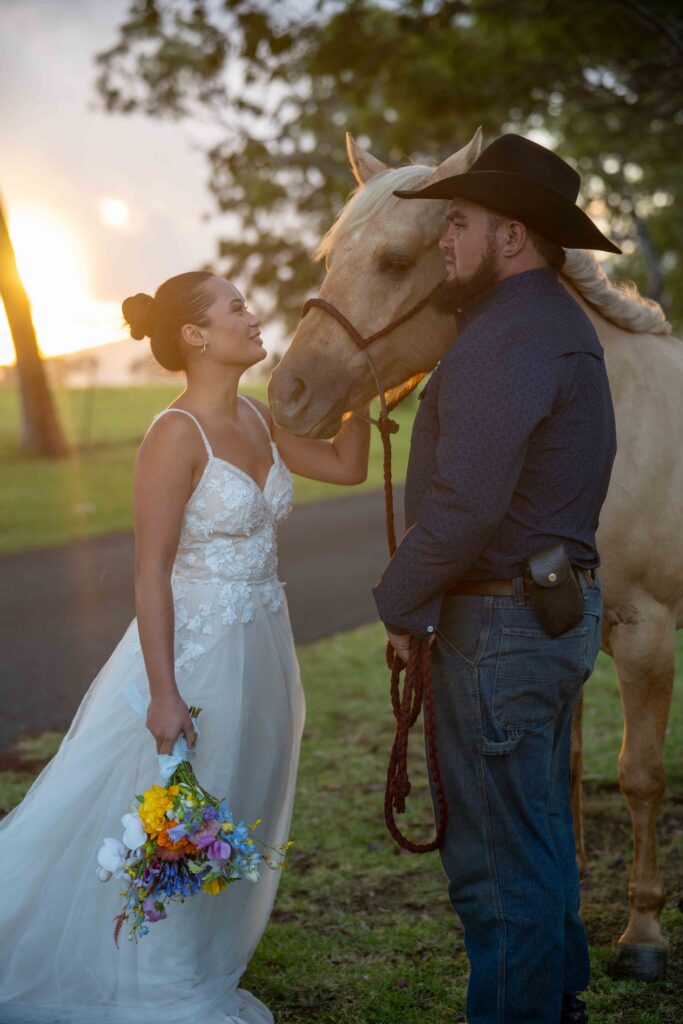 A couple in wedding clothes stand with a horse