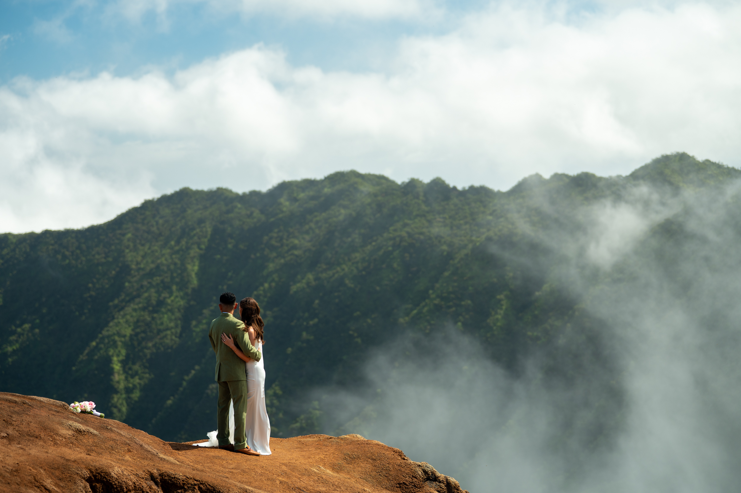 A couple looks out on Kalalau lookout in wedding clothes