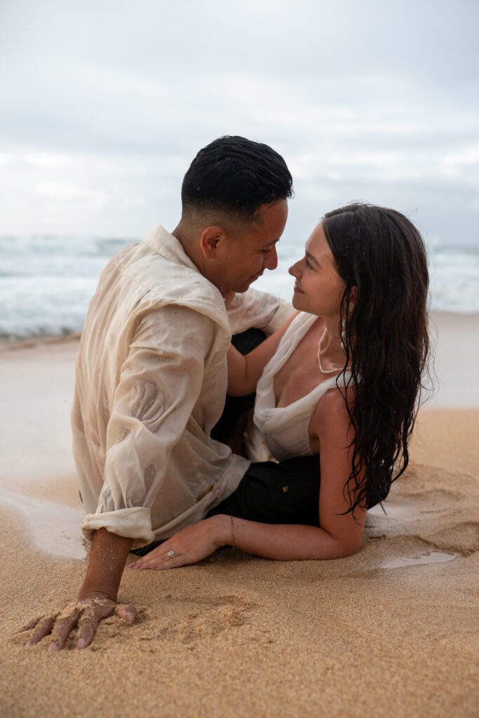 a couple plays in the waves in their wedding clothes after their Kauai elopement
