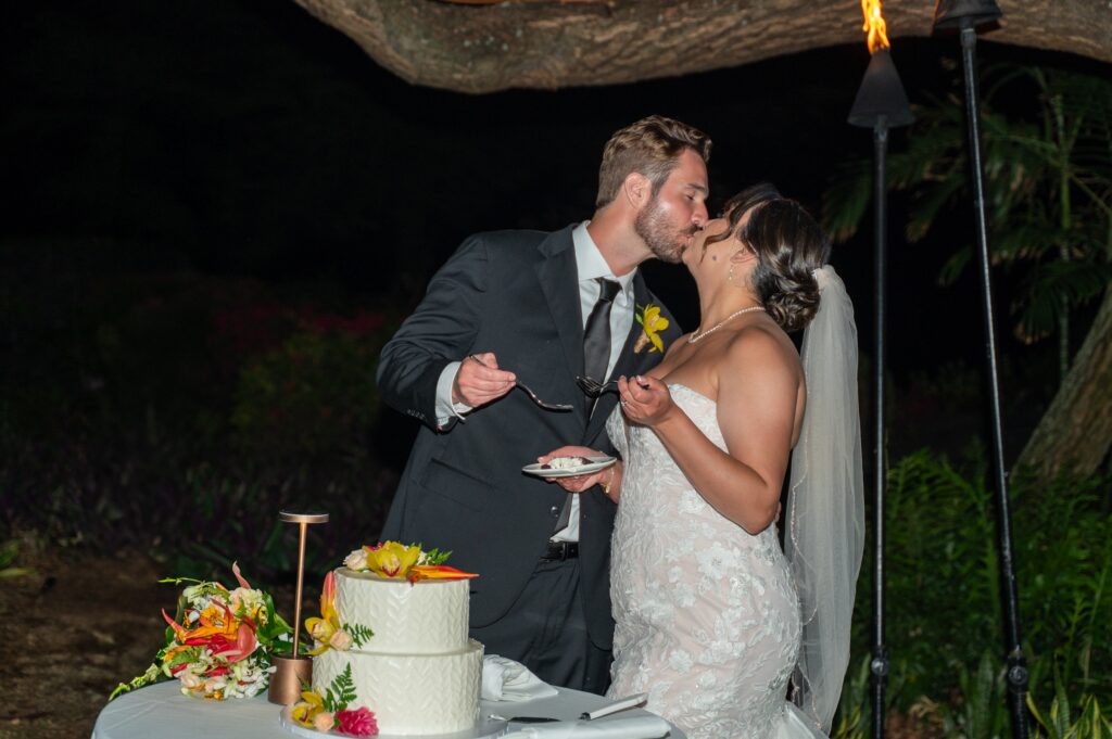 A bride and groom eat cake in the Helani gardens at their Outrigger Kona wedding